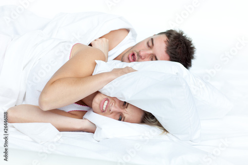 upset woman in bed with her boyfriend snoring