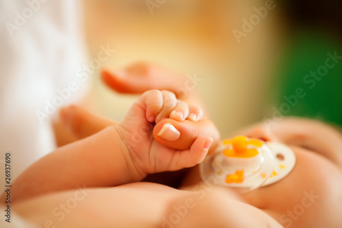 Baby mit Mutter greift nach Hand