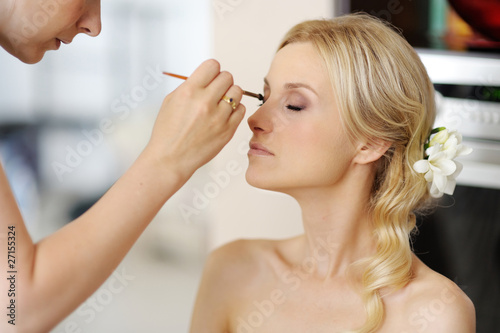 Young beautiful bride applying wedding make-up