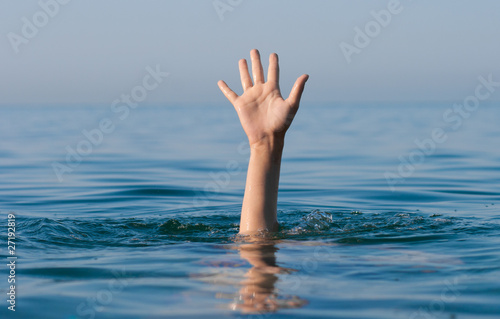 single hand of drowning man in sea asking for help