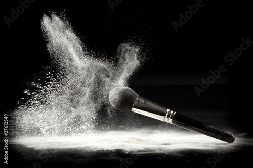 a composition with a powder brush and white loose powder