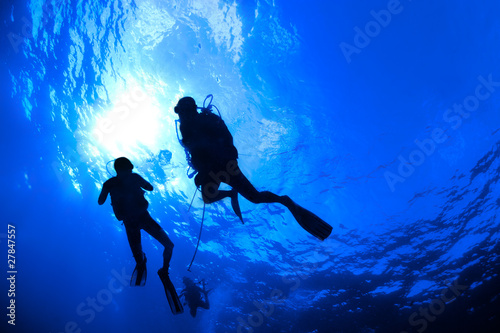 Scuba Divers in silhouet with sunburst on blue background