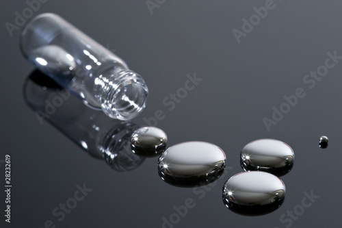 Mercury and glass container on a reflective surface.