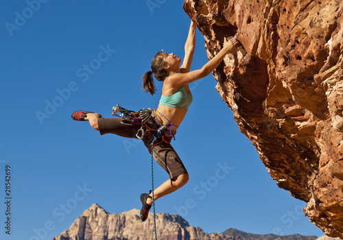 Female rock climber clinging to a cliff.