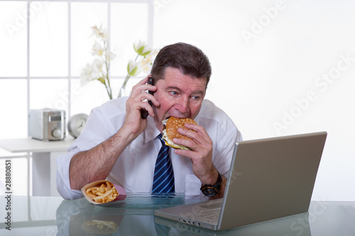 man at office with phone eat unhealthy food