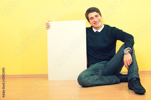 Portrait of a handsome smiling young man sitting and holding a b