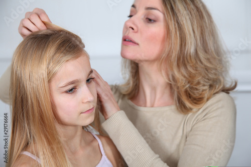 Mother treating daughter's hair against lice