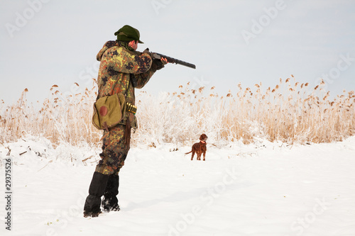 Hunter aiming at the prey, dog waiting