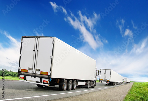 caravan of white trucks on highway under blue sky