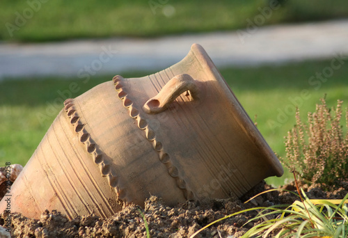 Ancient amphora on green grass in daylight