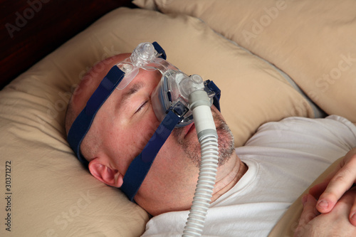 Man with sleep apnea using a CPAP machine in bed.