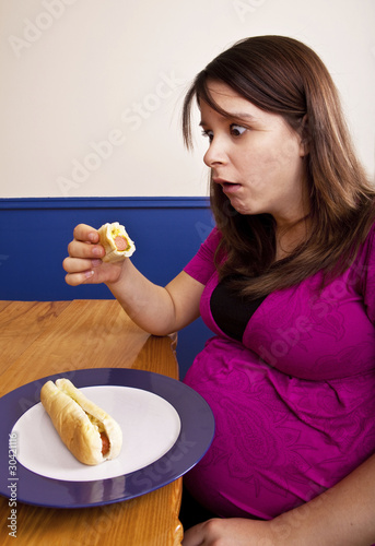 Young pregnant woman eating junk food dumb expression