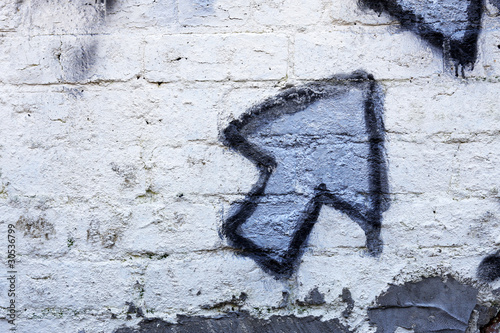 Blue graffiti arrow on a whitewashed brick wall
