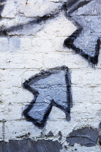 Blue graffiti arrows on a whitewashed brick wall