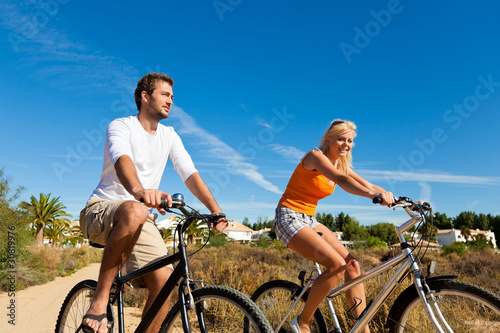 Couple in holidays cycling on beach