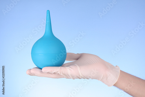 Small enema on hand with blue background