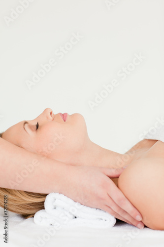 Pretty blond-haired woman lying down while receiving a spa treat