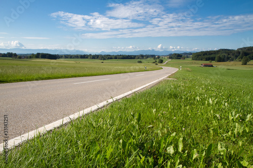 Landstrasse in Bayern im Frühjahr mit Alpenblick