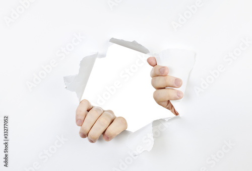 Hands ripping through hole in paper
