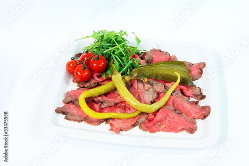 Roastbeef with gherkin and hot pepper on white background