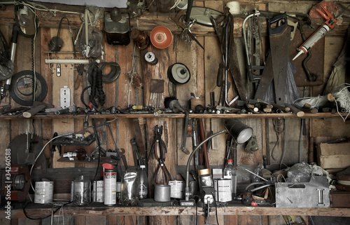 many different old tools hanging on a barn wall