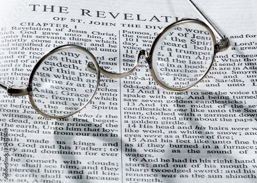 Antique reading glasses on page of bible