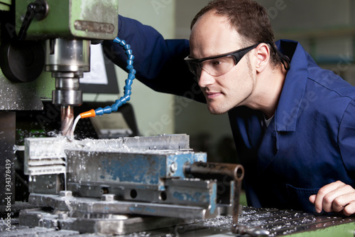 Laborer at milling machine.