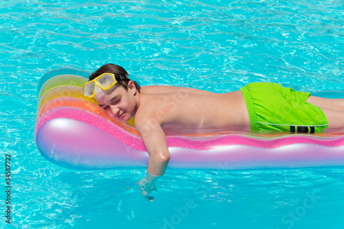 Boy resting on lilo in pool