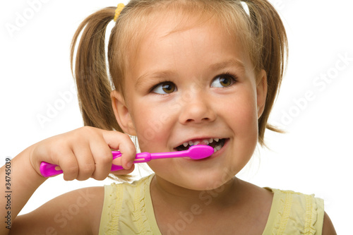 Little girl is cleaning teeth using toothbrush
