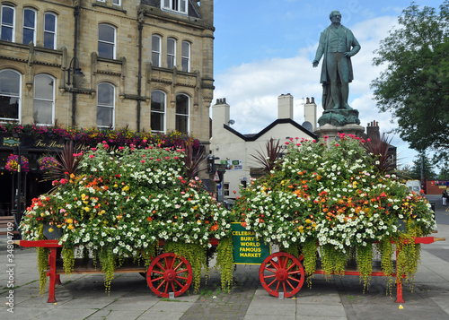 A statue and a pretty floral display on barrows in the Lancashire market town of Bury Greater Manchester U.K..