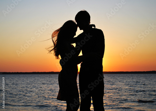 Silhouettes of amorous couple on a background of a sunset