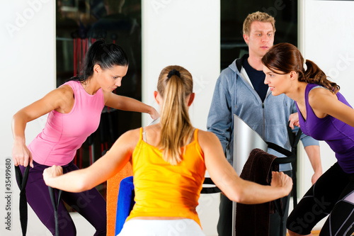 Frauen und Trainer in Fitness Studio vor Trainingsmaschine