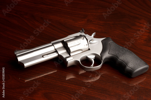 Clean .357 revolver laying on reflective wooden table