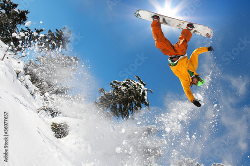 Snowboarder jumping against blue sky