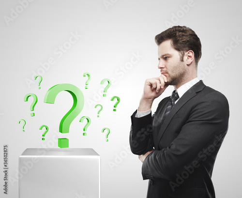 Young businessman look at the green question marks