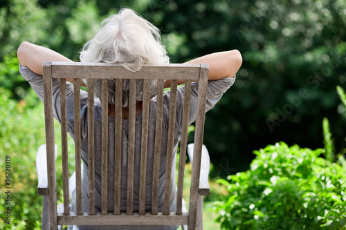 grauhaarige Frau entspannt im Garten