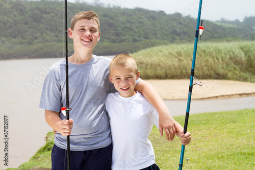 portrait of two little brothers fishing by the lake