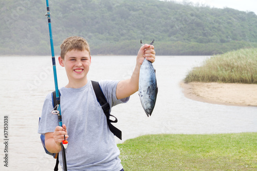 happy teen boy showing a fishing he just caught
