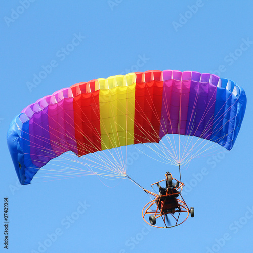 Colorful paraglider on blue bright sky