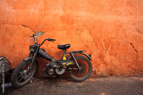 Old moped leans against an orange wall