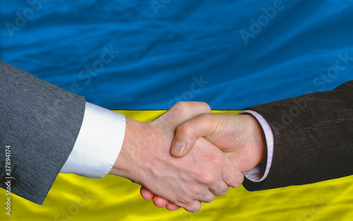 businessmen handshake after good deal in front of ukraine flag