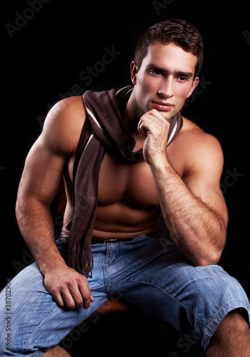 young muscular man sitting on a chair and thinking