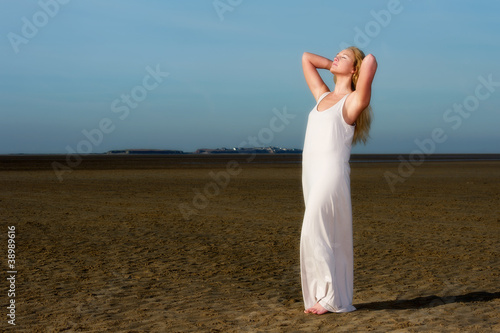 Pretty young woman in dress on beach