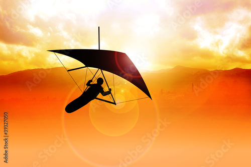 Silhouette of a man figure gliding during sunrise