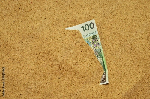 Banknot wystający z piasku