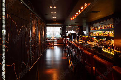 bar counter with red tall chairs in empty restaurant