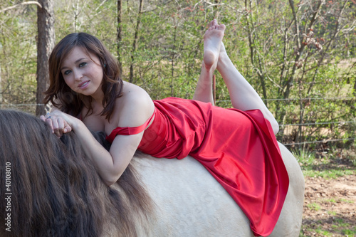 Woman in red dress riding a horse bareback