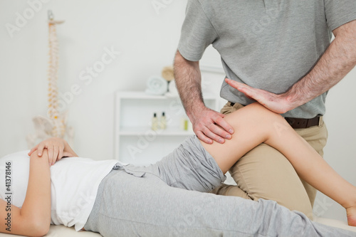 Serious osteopath massaging the knee of a patient