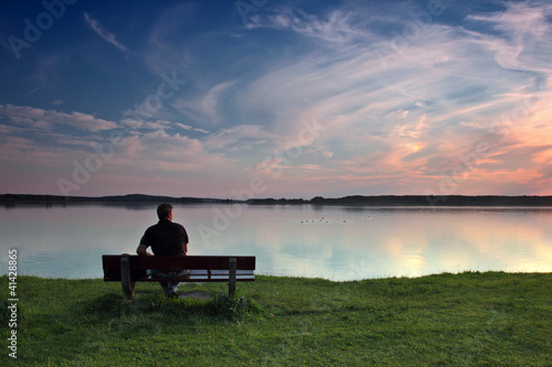 Mann auf Bank am See