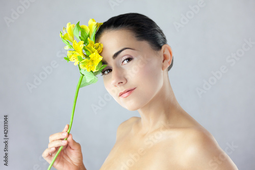 Twarz pięknej kobiety z uśmiechem i kwiatem w dłoni